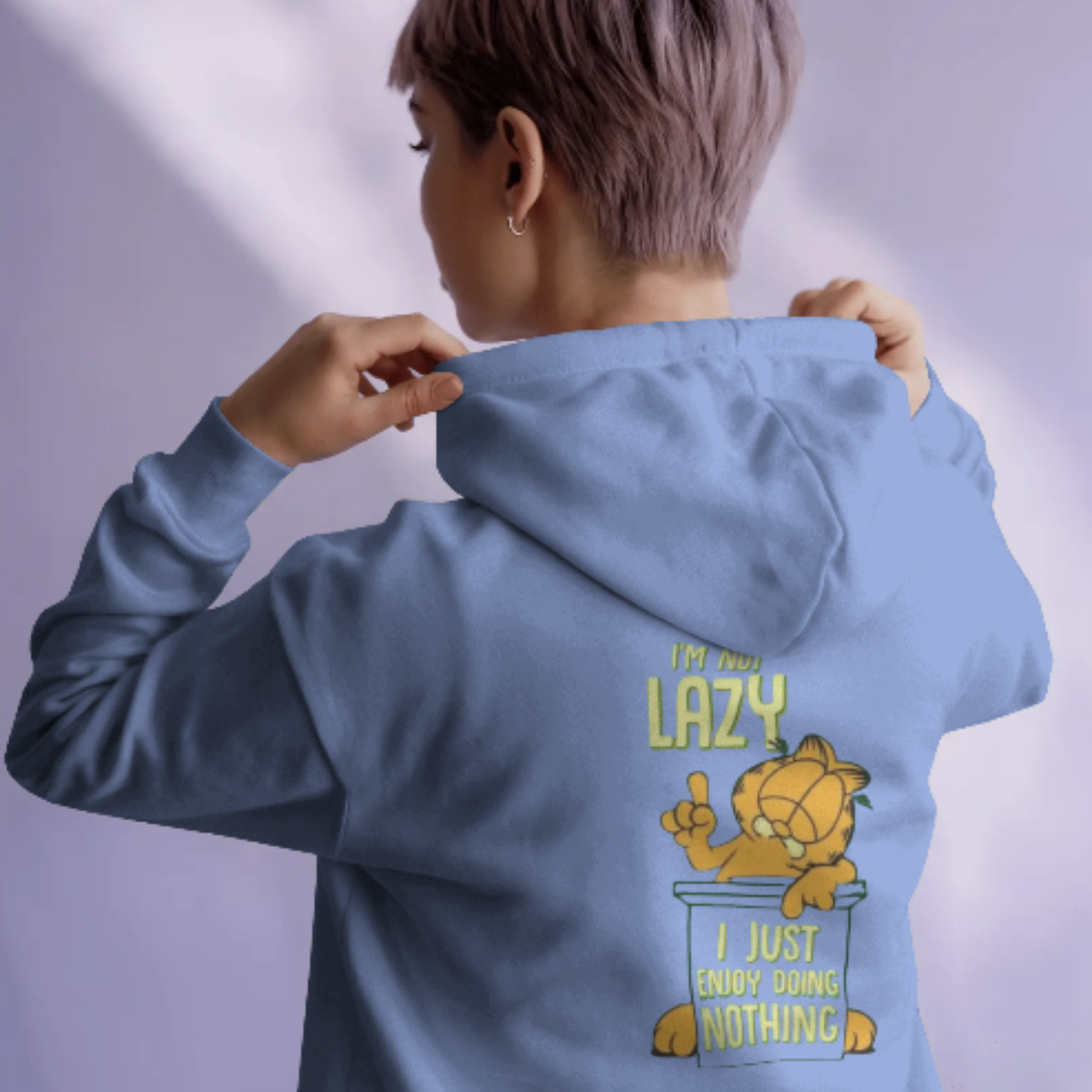 A person wearing a white hoodie with a "I'm not lazy, I just don't care" graphic featuring Garfield on the back.