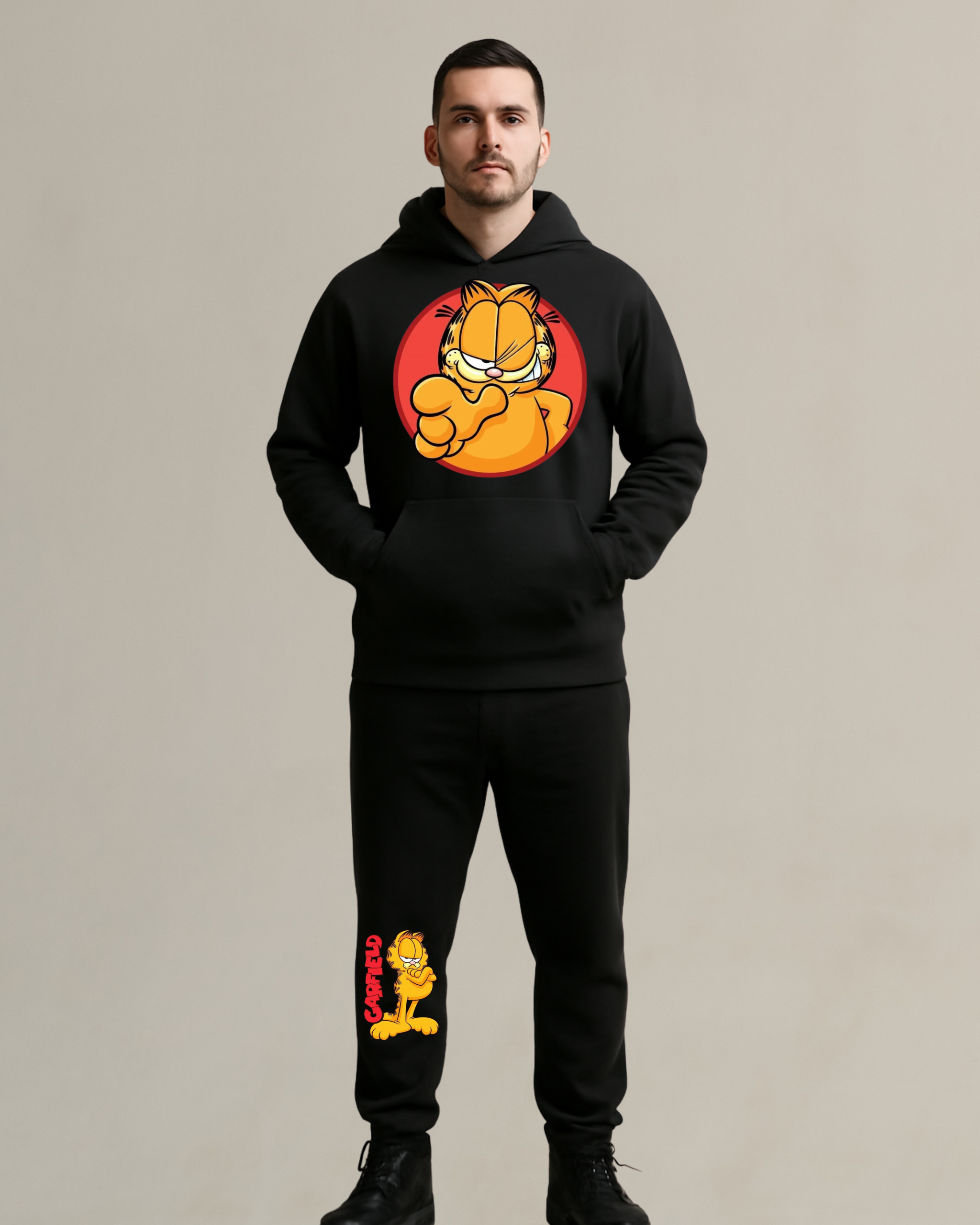 A man wearing a black Garfield co-ord set featuring a hoodie with a bold Garfield graphic on the chest and matching joggers with a Garfield print on the leg.