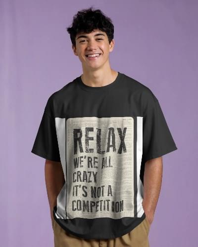 Smiling young man wearing a black t-shirt with a bold newspaper-style graphic that reads "RELAX. We're all crazy. It's not a competition."